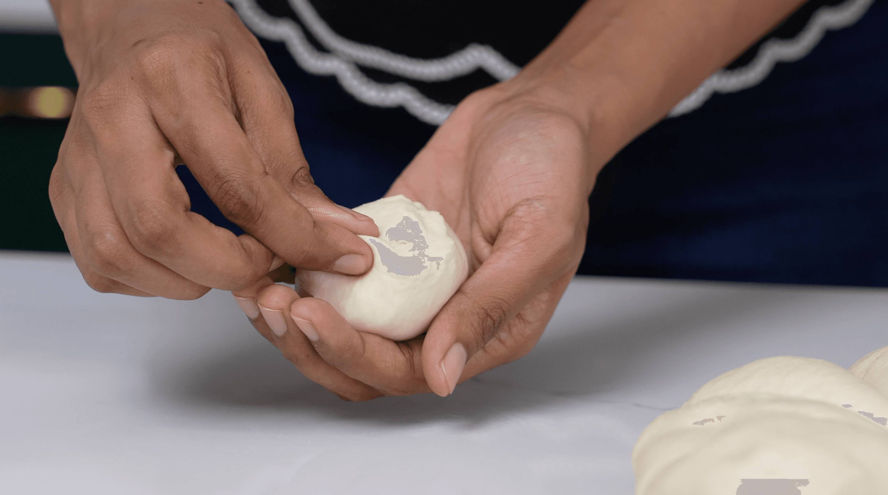 Hands shaping dough on a clean work surface